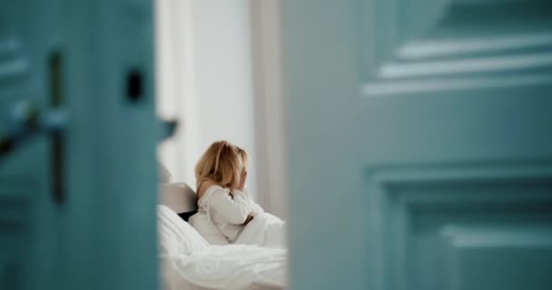 Soğuk algınlığı olan izole sarışın kadın hapşırıyor ve korkunç baş ağrısı ve sıcaklıktan muzdarip. O, yatakta dinleniyor. 4k görüntü. — Stok video
