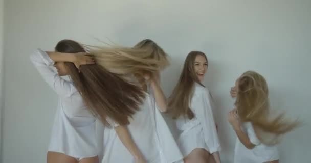 흰색 셔츠와 바지를 입은 네 명의 매력적 인 여자 친구들. 행복 한 여성들은 활발히 춤추고 있으며 스튜디오에서 자연 스러운 금발 머리를 흔들고 있다.. — 비디오