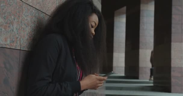 Side Portrait Junge Schöne Charmante Afrikanische Mädchen Hören Musik Kopfhörer SMS Chat Mobile Outdoor 4k Allein Tanzen Emotional Lustig. — Stockvideo