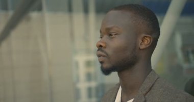 4K görüntülerinde, takım elbiseli ciddi modaya uygun bir Afrikalı sokakta güneş gözlüğünü takıyor..