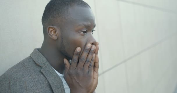 Le bel homme africain désespéré. L'homme malheureux se gratte la tête émotionnellement. Portrait latéral. Des images 4k. Extérieur. — Video