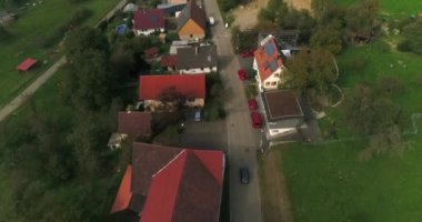 Helikopter, Almanya köyünde yol boyunca, kır evleri ve güzel yeşil doğası olan siyah arabanın üzerinde uçuyor. Üst görünüm, 4k görüntü.