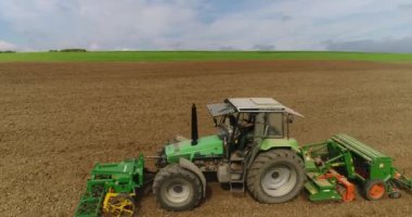 Tarım kavramı. Traktör hasat tarlasında çalışıyor. Hareket halindeki helikopter geri döndü. Büyüleyici Alman köyünün güzel manzarası.