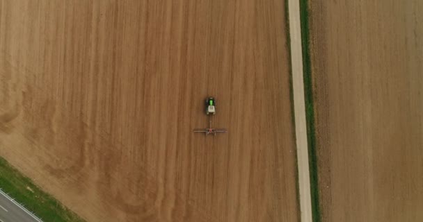 Helikopter naar beneden. Het bovenaanzicht van de trekker die in het Duits op het oogstveld werkt. 4k-beelden. — Stockvideo