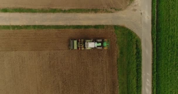 Copter steigt auf. Blick auf den Traktor, der auf dem Erntefeld arbeitet. 4k Filmmaterial. — Stockvideo