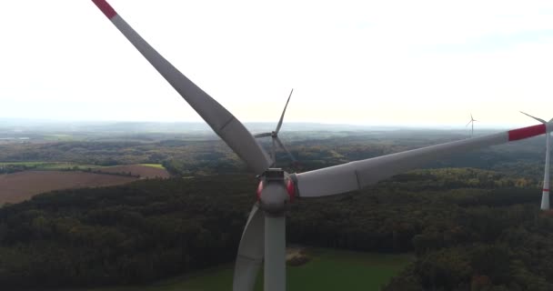 Visão traseira forma helicóptero nos moinhos de vento modernos rotativos no campo dourado e florestas verdes da Alemanha. Filmagem 4k. — Vídeo de Stock
