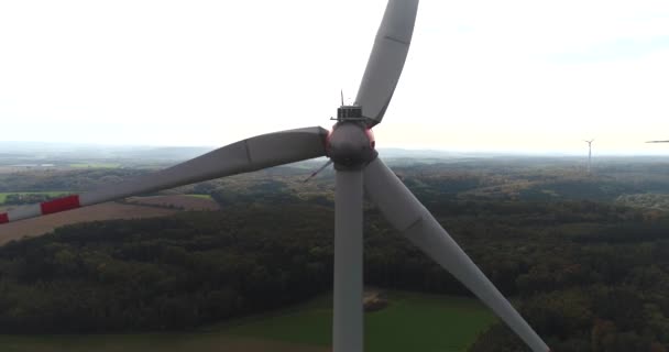 Vista posteriore della turbina eolica rotante sullo sfondo del bellissimo panorama naturale della Germania. Incantevoli campi d'oro e foresta verde. — Video Stock