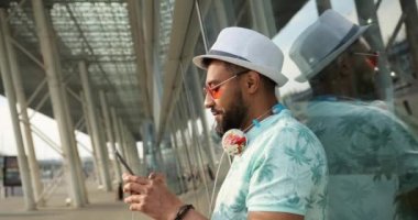 İnsanlar ve Teknoloji. Rahat Afrikalı adam SMS 'i iyi haberlerle aldığı için mutlu. Modern havaalanı yakınlarında uçağını bekliyor. 4k görüntü.