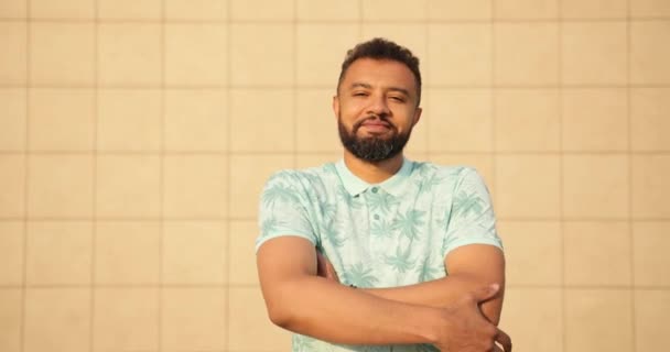 Portrait du jeune homme africain attirant en t-shirt pliant les bras et regardant la caméra au-dessus du mur jaune. 4k. — Video