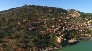 Antalya ilinin Akdeniz kıyısındaki Antalya kenti üzerinde uçan helikopterin ve güneşli Alanya kasabasının manzarası. Yavaş çekim, 4k.