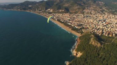 Türkiye 'nin Antalya ilindeki Taurus dağlarının kayalık tepelerindeki ünlü Kale, güzel Alanya, Akdeniz üzerinde uçan paraşütçü uçağının insansız hava aracı görüntüsü.