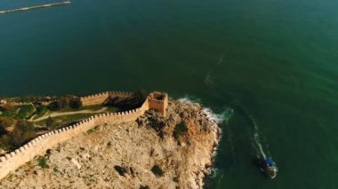 Eski Alanya kalesinin üzerinde, Akdeniz tarafından aşırı yıkanmış kayaların üzerinde helikopter uçuşu. Antalya, Türkiye.