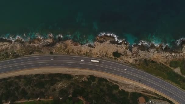 Aerial drone footage of the narrow road covered with driving cars near Mediterranean sea in Turkey. Top citrling view. Road on the rocky coastline. — Stock Video