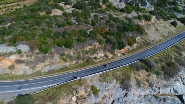 Θέα από drone στο motocyclist ιππασίας κατά μήκος του στενού δρόμου σε όμορφα βουνά του Ταύρου πλημμυρισμένη από τη Μεσόγειο θάλασσα στην ηλιόλουστη Gazipasa, επαρχία Αττάλειας στην Τουρκία. — Αρχείο Βίντεο
