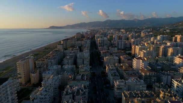 Mahmultar al atardecer. Provincia de Antalya en Turquía. Copter volador sobre la ciudad y la costa con olas rompientes del mar Mediterráneo y rodeado de montañas Tauro. — Vídeos de Stock