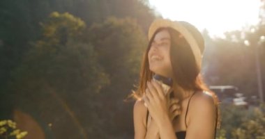 Romantik ve mutlu genç kadın akıllı telefonunu tutar ve akşam güneşinin altında durup gülümser dağlarda bir yerlerde. Yaz günleri