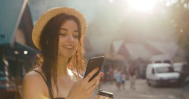 Affascinante giovane donna con i capelli bagnati sta in bikini e legge qualcosa nel suo smartphone. Ora legale, vocazione — Video Stock