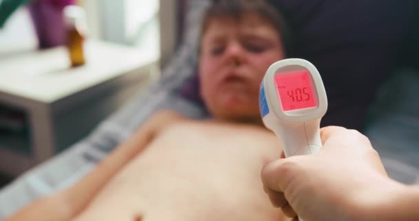 Virussjukdom. Mässlingutslag. Barn med virusinfektion mässling ligger i sängen. Mamma mäter pojkarnas temperatur. 40,5. Mycket sjuk — Stockvideo