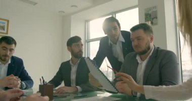Bir grup genç iş adamı bir araya gelir ve modern, parlak bir ofis alanında çalışırlar. Toplantı. Bir grup genç, ofiste birlikte otururken bir şeyler tartışıyorlar..