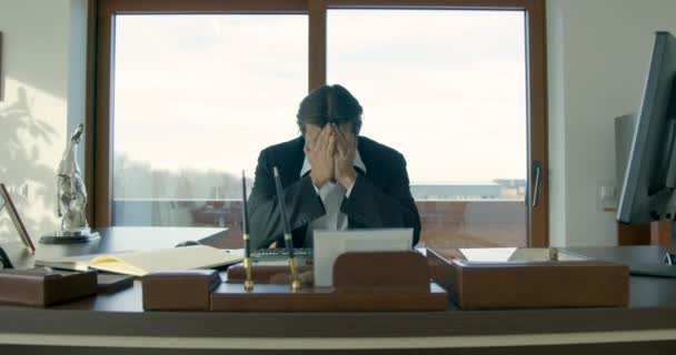 Egy nagyon szomorú ember ül az irodában, és a kezével takarja el az arcát. Depresszió. Üzleti problémák. — Stock videók