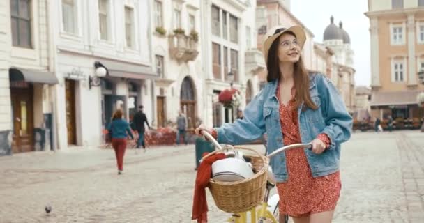 Eski Avrupa kasabasında genç bir vahşi erkek turist. Kırmızı elbiseli çekici genç bir kadın bisikletle yürüyor ve güzel mimariye bakıyor. — Stok video