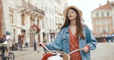 Eski Avrupa kasabasında genç bir vahşi erkek turist. Kırmızı elbiseli çekici genç bir kadın bisikletle yürüyor ve güzel mimariye bakıyor.