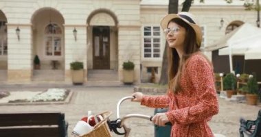 Eski Avrupa kasabasında genç bir vahşi erkek turist. Kırmızı elbiseli çekici genç bir kadın bisikletle yürüyor ve güzel mimariye bakıyor.