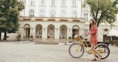 Eski Avrupa kasabasında genç bir vahşi erkek turist. Kırmızı elbiseli çekici genç bir kadın bisikletle yürüyor ve güzel mimariye bakıyor.