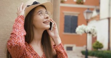 Genç kız ve teknoloji. Genç bir kadın bisikletin yanında duruyor ve akıllı telefonuyla güzel mimariye bakan biriyle konuşuyor.