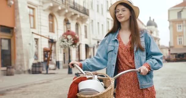 古いヨーロッパの町の若い女性観光客。赤いドレスの魅力的な若い女性は自転車で歩き、美しい建築を見て回る — ストック動画