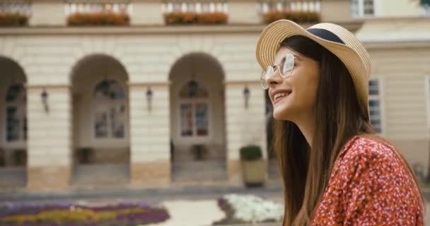 Young fermale tourist in old European town. Charming young woman in red dress walks with a bicycle and looks around at beautiful architecture — Stock Video