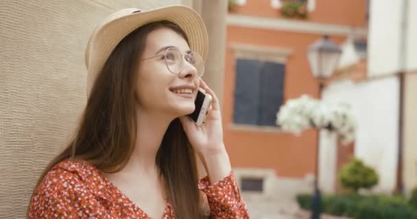 Junges Mädchen und Technologie. Junge Frau steht am Fahrrad und spricht mit jemandem auf ihrem Smartphone, der die schöne Architektur betrachtet — Stockvideo