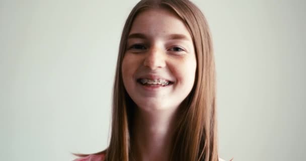 Okouzlující usmívající se dívka s blond vlasy pihy a rovnátka pohled do kamery. Detailní záběr portrétu. — Stock video