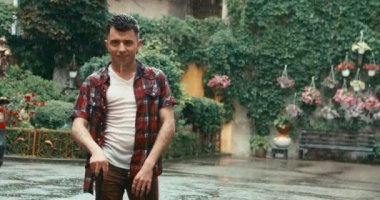 Bastonlu çekici esmer adam sokakta yağmurun tadını çıkarıyor. 4k görüntü.