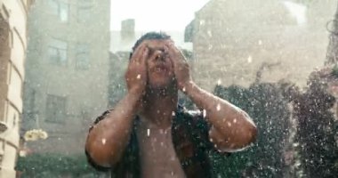 Güneşli bir günde genç esmer yukarı bakıyor ve yüzüne dokunuyor. Gökkuşağının manzarası. 4k görüntü.