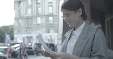 Gözlüklü başarılı bir iş kadını dışarıda belgeleri okuyor. Evet. 4k.