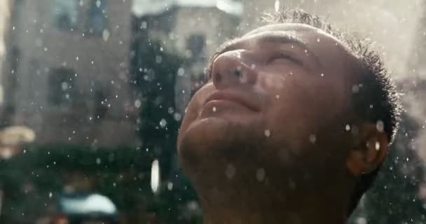 Retrato de cerca del hombre relajado mirando hacia arriba bajo la lluvia. Imágenes de 4k. — Vídeo de stock
