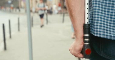 Sokakta koltuk değneğiyle yürüyen kimliği belirsiz adamın yakın görüntüsü. 4k.