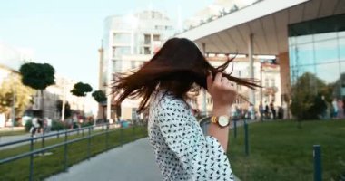 Açık havada kulaklıkla müzik dinlerken neşeli, çekici, genç bir esmerin duygusal portresi. 4k görüntü.