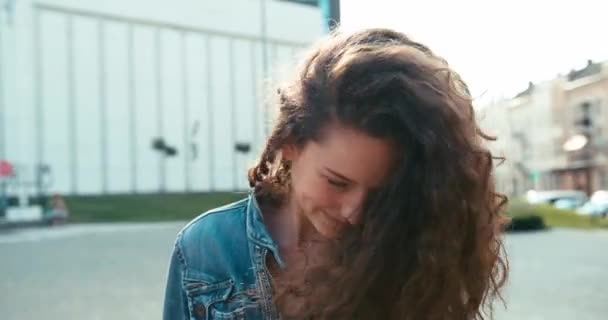 Portret Charmant aantrekkelijk meisje mooie glimlach schudt donker krullend haar outdoor 4k Beelden. — Stockvideo