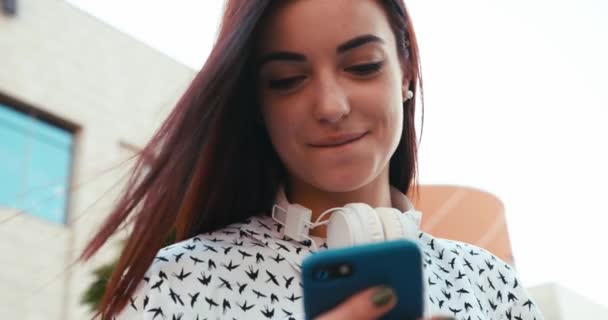 Ritratto dell'adorabile bruna sorridente che messaggia e naviga tramite il telefono cellulare all'aperto. — Video Stock