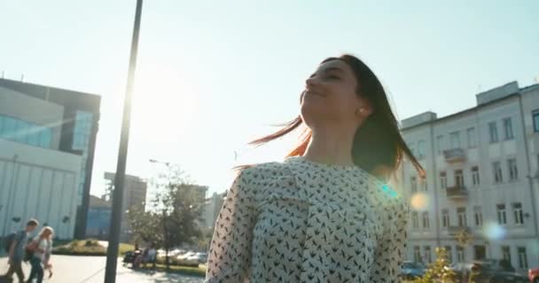 Nádherná usměvavá sebevědomá bruneta kráčí po slunné ulici a třídění jejích vlasů. — Stock video