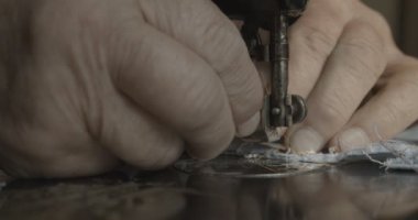 Bilinmeyen yaşlı erkek elleri eski el yapımı makineye dikiş dikiyor. Çalışmak için hazırlık. İpliği makineye sokuyor. 4k.
