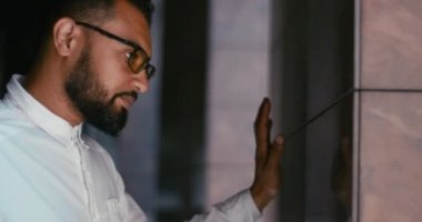 Depresyonda duvara yaslanan zarif endişeli Afrikalı adamın yan portresi. 4k görüntü.