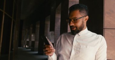 Neşeli, yakışıklı Afrikalı adam mesajları iyi haberlerle alıyor. Duyguların ifadesi. 4k.