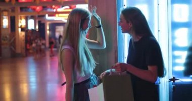 Başarılı bir alışverişin ardından yürüyen iki genç bayan, gülümseyerek ellerinde renkli paketler taşıyorlar. Şık kızlar alışveriş merkezinde gezip eğleniyor. Heyecan verici bir konuşma.