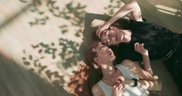 Retrato al aire libre de hermosas chicas jóvenes. Chicas soñadoras que atrapan los rayos del sol. Gemelos felices. Dos amigos sonrientes mienten y sueñan. Adolescentes divirtiéndose en un ambiente informal. Chicas mentirosas con — Vídeo de stock