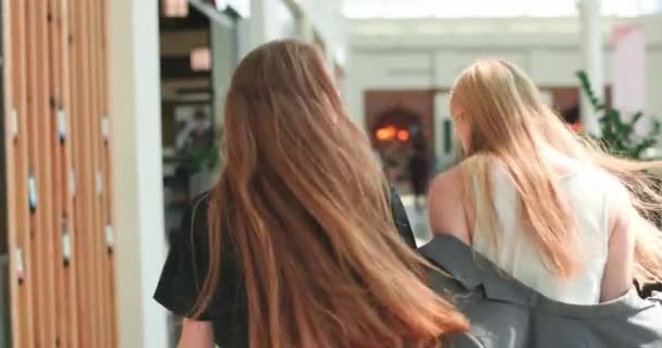 Amici alla moda camminano nel centro commerciale, ridono e si abbracciano. Gli amici felici vanno a casa dopo aver fatto shopping con successo. Video 4K — Video Stock