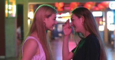 Eğlenen iki güzel kız arkadaşın yaşam tarzı portresini kapat. Çekici, mutlu, genç bir kadının güzel portresi. Bakışlarını kaçırmadan birbirlerine bakıp, gülümseyen ve davetsiz bir misafiri yöneten.