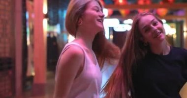 İçeride dans eden çekici genç bir kadının portresi. Saçlarıyla oynayan ve eğlenen, günlük kıyafetler ve altın aksesuarlar giyen, parlak renkler giyen iki güzel kız arkadaşın hayat tarzı portresi.